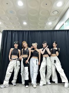 four girls in white pants and black tops posing for the camera with their hands on their hips