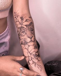 a woman's arm with flowers and a cheetah tattoo