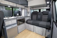 the interior of a camper with grey and black seats, stove, sink and oven