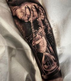 a man's arm with an hourglass tattoo on it