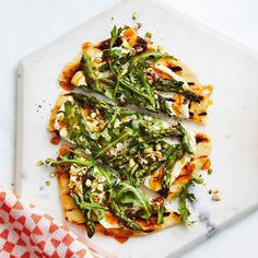 a pizza topped with asparagus and other toppings on a white plate next to a red checkered napkin