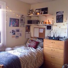 a dorm room with a bed, desk and shelves on the wall next to it