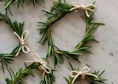 four rosemary sprigs tied with twine on a white marble counter top, ready to be used as christmas decorations