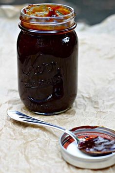 a glass jar filled with liquid sitting on top of a table next to a spoon