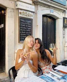 two women sitting at a table with wine glasses