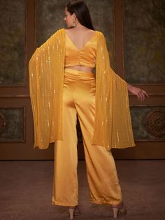 This is a two-piece Yellow Butterfly Drape Top Set from the Suruchi Parakh collection. The yellow butterfly twisted drape top in georgette is paired with satin silk straight pants. The butterfly style crop top has a back hook opening. There is beautiful sequin thread work all over the crop top. The yellow color with sequin, padding and long drape enhances the graceful, drape top set. Summer Party Palazzo Set With Cape Sleeves, Satin Party Wear Sets, Silk V-neck Party Sets, Spring Party Palazzo Set With Cape Sleeves, Chic Silk Pant Set For Party, Chic Silk Palazzo Set For Party, Yellow Summer Party Palazzo Set, Festive Yellow Pant Set For Party, Festive Yellow Party Pant Set