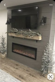 a living room with a fireplace and tv mounted on the wall, decorated for christmas