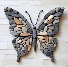 a butterfly made out of rocks sitting on top of a wall