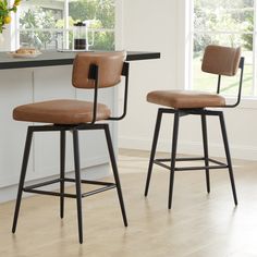 two brown barstools sitting next to each other in front of a kitchen counter