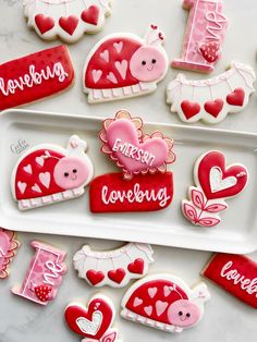 valentine's day decorated cookies are arranged on a white platter with pink and red accents