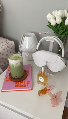 a white table topped with a vase filled with flowers next to a candle and book