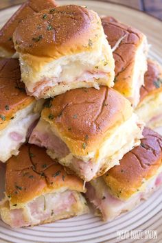 ham and cheese sliders stacked on top of each other on a plate with a wooden table in the background