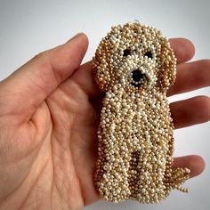 a hand is holding a beaded dog brooch