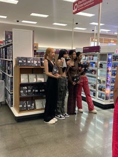 four girls standing in a store looking at their cell phones