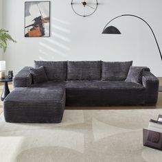 a living room with a sectional couch and large clock on the wall next to it