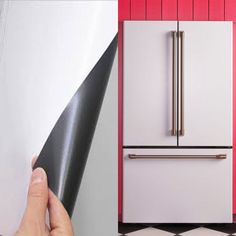 a person holding a black and white object in front of a pink refrigerator freezer