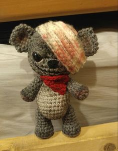 a crocheted teddy bear with a red scarf and hat on it's head