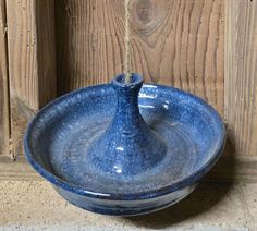 a blue bowl sitting on top of a wooden table next to a wall mounted hook