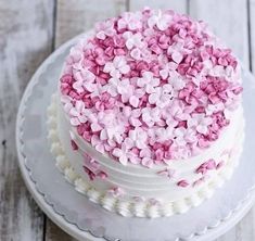 a white cake with pink and white flowers on it sitting on top of a plate