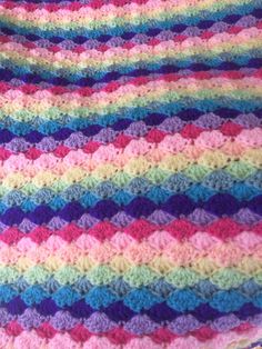 a multicolored crocheted blanket is laying on the floor