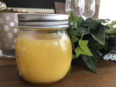 a glass jar filled with liquid sitting on top of a wooden table next to potted plants