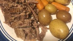 a white plate topped with meat, potatoes and carrots