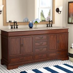 a bathroom vanity with two sinks and a large mirror above it, in front of a striped rug