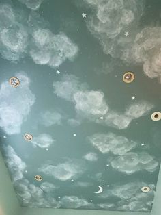 the ceiling is painted with clouds, stars and crescents in blue sky above a bed