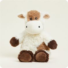 a brown and white stuffed cow sitting up against a white background