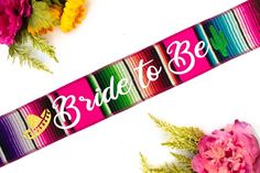 the bride to be sash is next to flowers