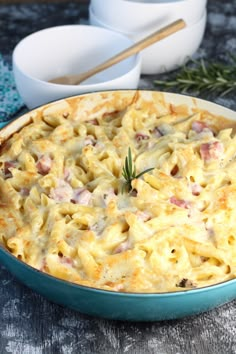 a casserole dish with ham and cheese in it on a table next to two bowls