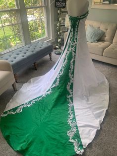 a green and white wedding dress on display in a room with couches, windows and furniture