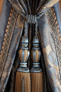 two tassels are attached to the back of a drapes with blue and gold fabric