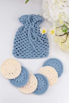 three crocheted blue and white items next to flowers