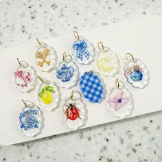 a bunch of small glass charms sitting on top of a white board next to each other