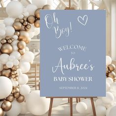 a baby shower sign surrounded by white and gold balloons