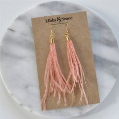 These elegant feather earrings are perfect for a wedding or any night out! The soft peachy blush shade works well as a neutral or as a fun accent. + lightweight blush ostrich feathers+ gold-plated ear wire hooks (lead-free and nickel-free)+ comes with plastic earring back for security+ approximately 5-6 inches long   (each piece is handmade so lengths are approximate)+ packaged on a hand-stamped kraft earring card in a clear resealing bag making them ready for gift givingMORE FEATHER EARRINGSTo Feather Earrings For Summer, Elegant Adjustable Feather Earrings, Elegant Pink Fringe Jewelry, Elegant Feather Earrings, Summer Party Earrings With Feathers, Feather Party Jewelry For Summer, Boho Wedding Earrings, Plastic Earrings, Ostrich Feather