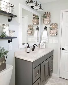 a bathroom with two sinks and mirrors on the wall next to a toilet in front of a mirror