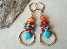 "This is a Statement Earrings. This striking pair of multi gemstone earrings features a beautiful orange artisan glass and a turquoise stone drop, suspended within a sculpted round hoop. Hoop is jeweled with 8 Diamond cut tiny crystals. Metal is plated in 18 karat gold. Earrings is highlighted with cluster of small turquoise and red coral stones. Hanging from a surgical steel lever-back, it measures 2\" in length. Earrings are light weight and sway gracefully as you move about your day. These co Vibrant Drop Earrings Jewelry Gift, Vibrant Drop Earrings For Gift, Vibrant Drop Earrings For Gifts, Vibrant Orange Round Bead Jewelry, Vibrant Orange Dangle Jewelry, Vibrant Orange Round Beaded Jewelry, Bohemian Multi-stone Dangle Earrings, Vibrant Red Dangle Jewelry, Vibrant Handmade Dangle Jewelry