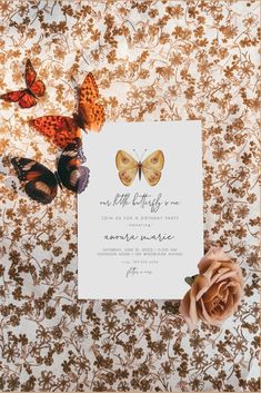 a card with butterflies on it next to a rose