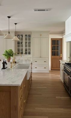 a large kitchen with white cabinets and wood floors