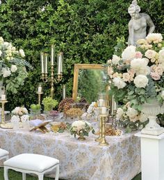 a table with flowers and candles on it in front of a mirror surrounded by greenery