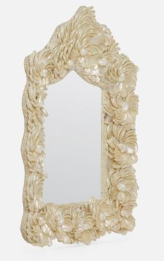 a decorative mirror made out of shells on a white background with the reflection in it