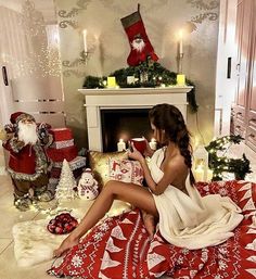 a woman sitting on the floor in front of a fireplace with christmas decorations around her