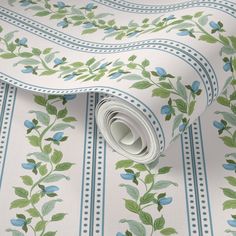 a wallpaper with blue flowers and green leaves on white background, rolled up to the floor