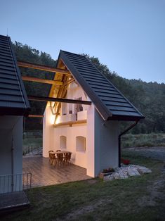 the house is lit up at night and has an open patio area with table and chairs