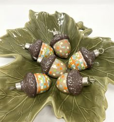 four ceramic ornaments sitting on top of a leaf shaped dish with polka dots and green leaves