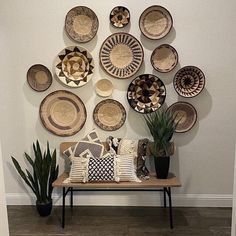 a room with many plates on the wall and plants in vases next to it