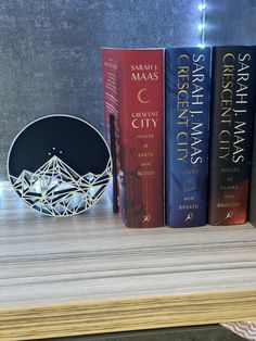 three books sitting on top of a wooden shelf next to a clock and other items