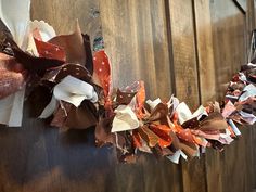 a bunch of different colored ribbons hanging on a wooden wall with wood boards in the background